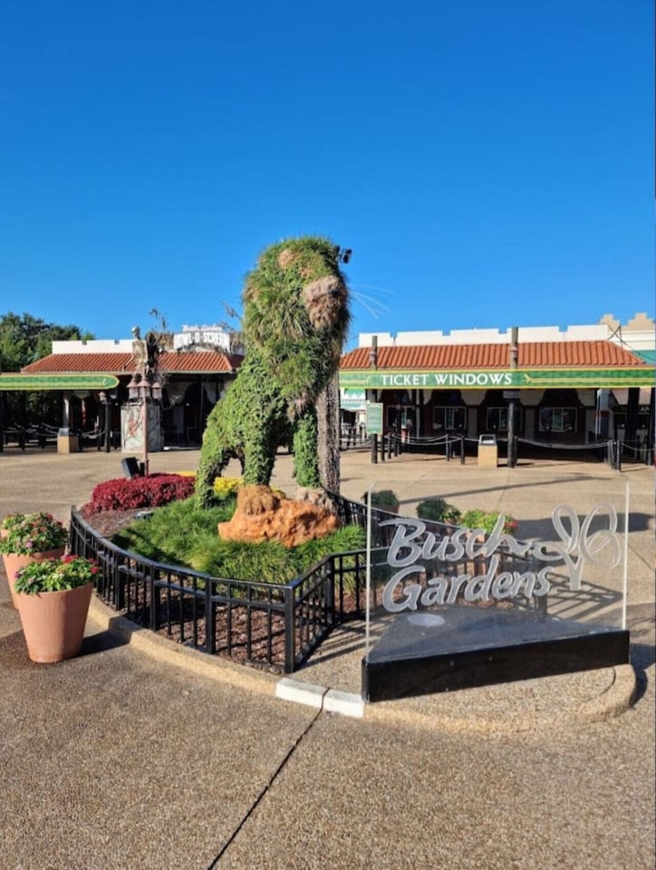 Un jardín con una estatua, una ventanilla de venta de entradas y un cartel que dice 'Bisch Gardens'.
