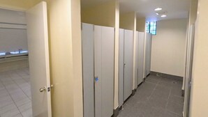 A row of single-occupancy restrooms with individual stalls, a tiled floor, and a plain wall design. - The Luneta Seafarers Center Premier Dorm (Manila)