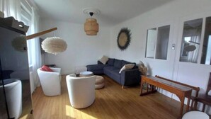Una sala moderna con un sofá azul oscuro, poufs blancos y una mesa de centro de madera.