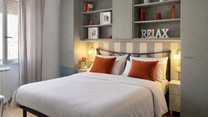 Ein modernes Schlafzimmer mit Bett, Nachttischen, einem an der Wand befestigten Regal mit Dekoration und einem Schild mit der Aufschrift 'RELAX'.