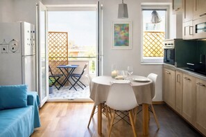 A modern kitchen with wooden cabinets, a dining table set for two, and a balcony with a view. - Cozy, bright apartment with a balcony for three people; pets allowed (Cagliari)