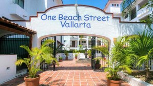 The entrance to One Beach Street Vallarta with a tiled pathway and potted plants. - Beachfront One Beach Street Condo - Pool - In the Heart of Old Town PV (Puerto Vallarta)