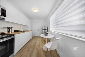 Eine moderne Küche mit weißen Schränken, einem eingebauten Backofen und einem Edelstahl-Kühlschrank.