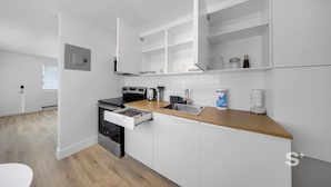 Une cuisine moderne avec des meubles blancs, un plan de travail en bois et des appareils électroménagers en acier inoxydable.