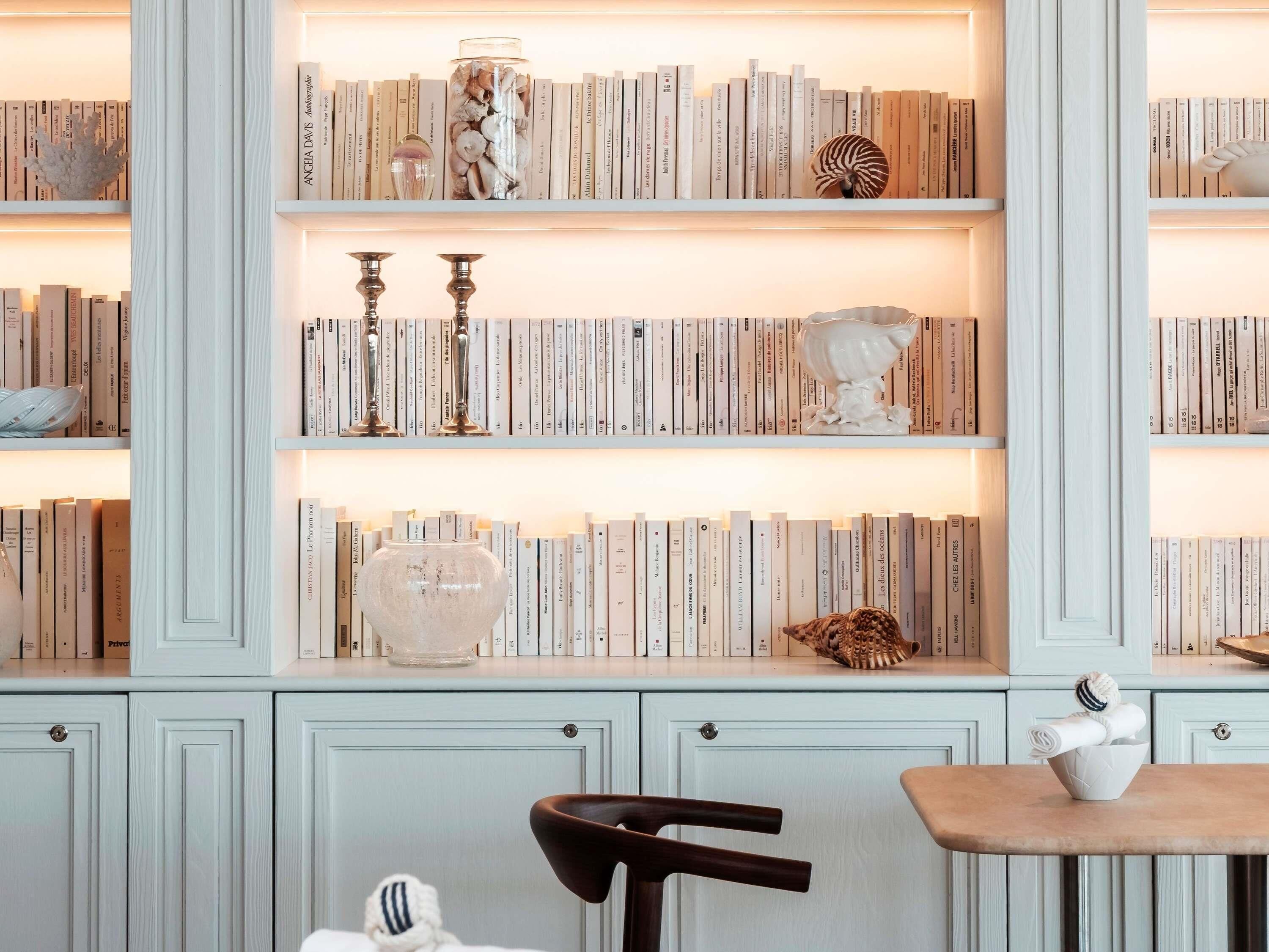 A bookshelf with books, decorative items, and a chair.