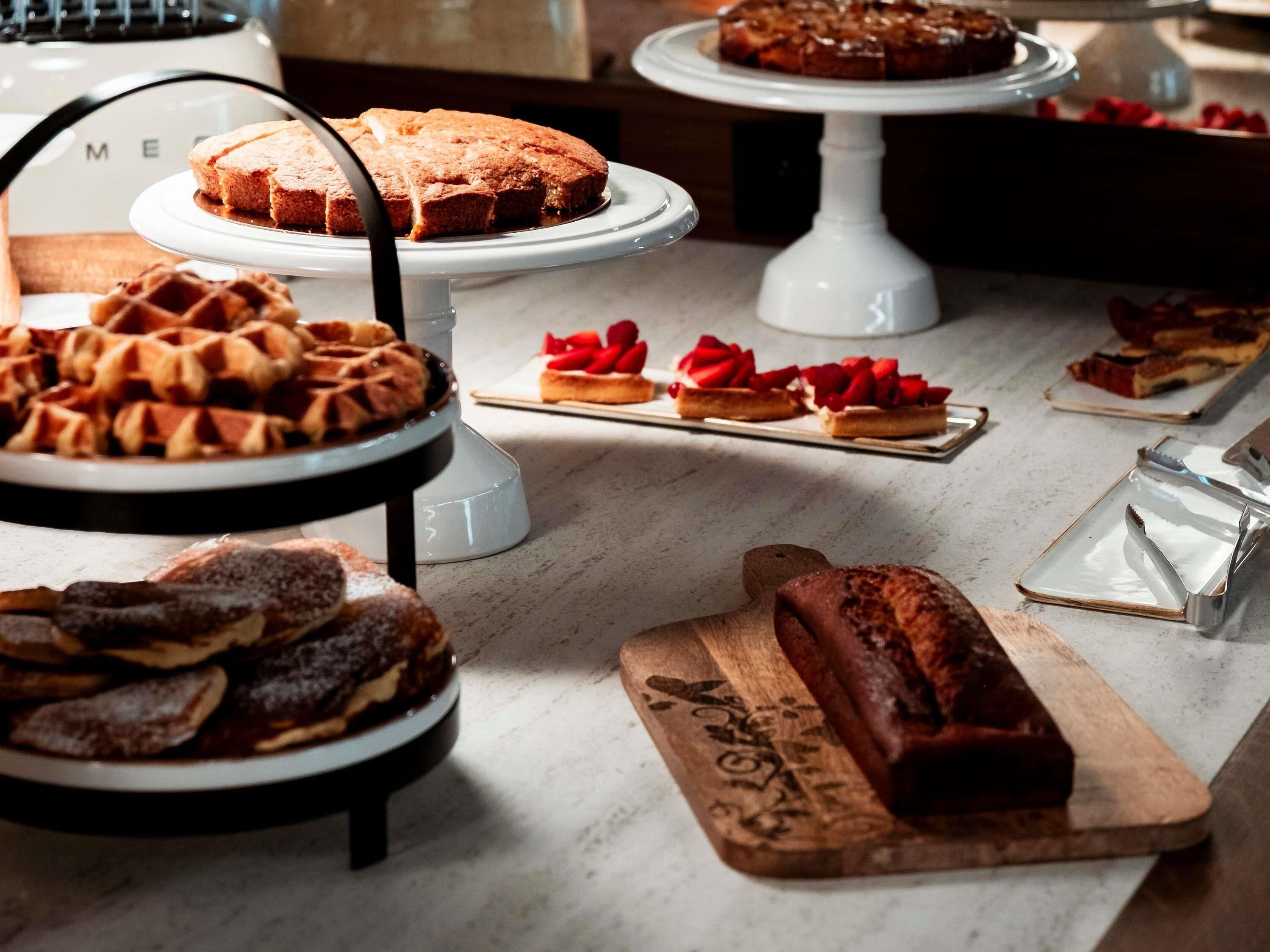 A variety of desserts on display, including cakes, waffles, and pastries.