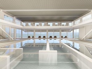 Un hôtel moderne avec un intérieur contemporain, une piscine centrale, des balcons et une vue sur l’océan.