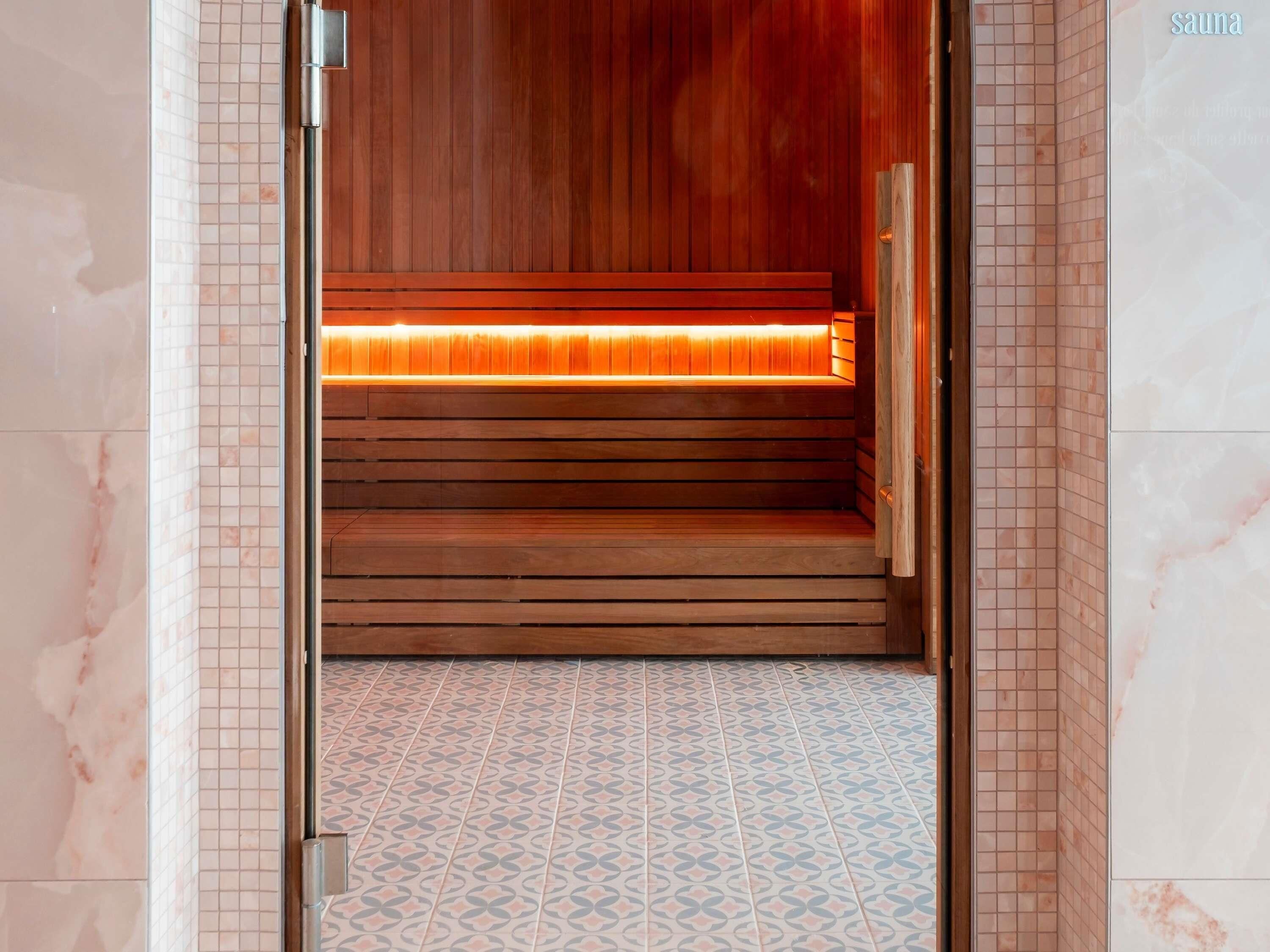 Eine Sauna mit Holzbänken und gefliestem Boden.
