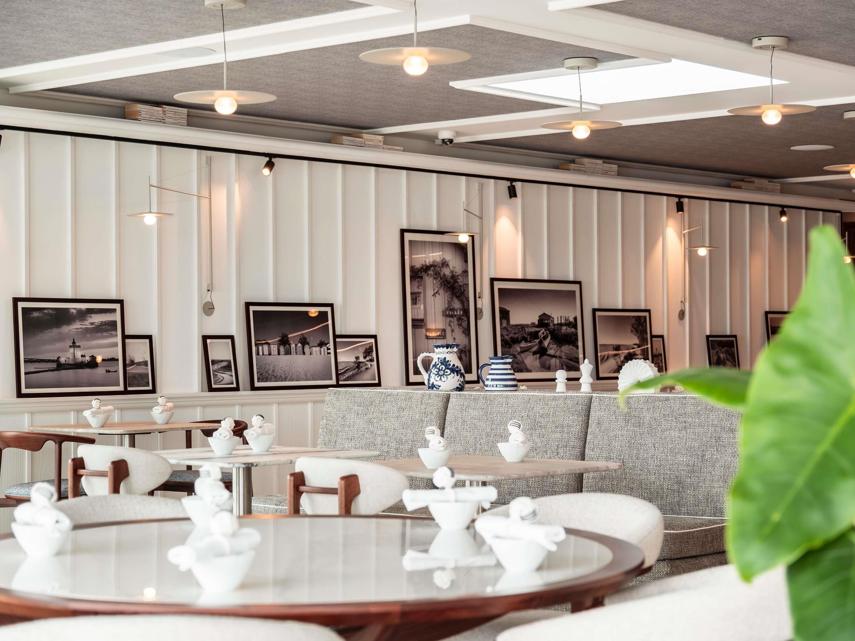 A modern dining area with round tables, white teapots, and framed pictures on the wall.