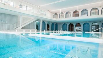 Una piscina techada, sillones reclinables de piscina