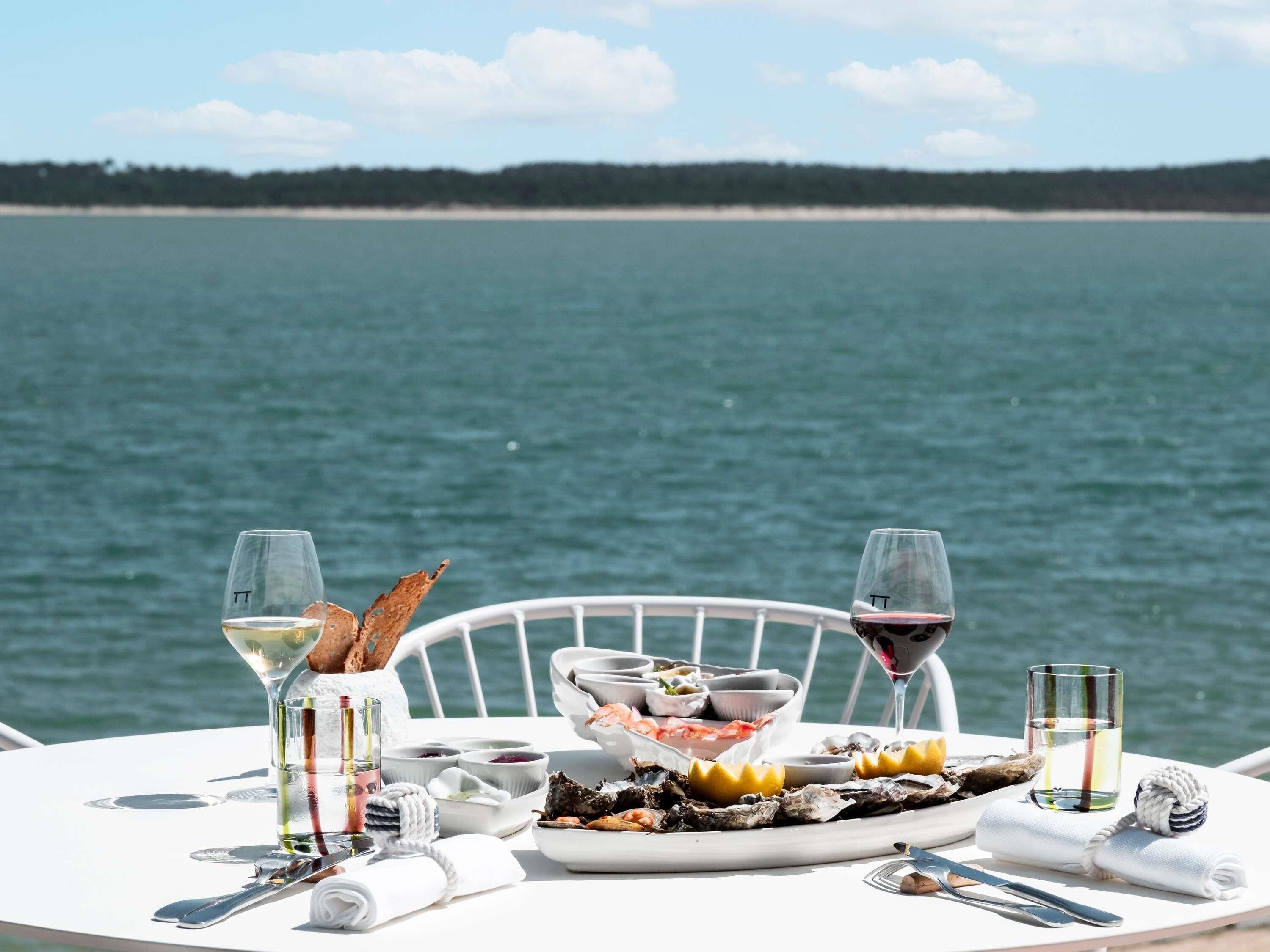 A table set with seafood, wine glasses, and a scenic view of the water.