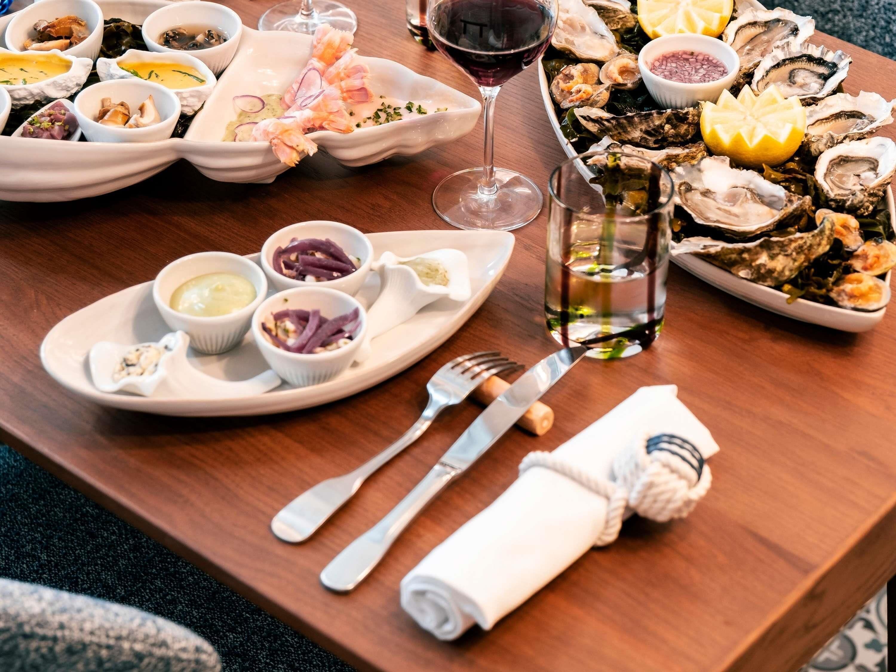 A dining table with various seafood dishes, a wine glass, and cutlery.