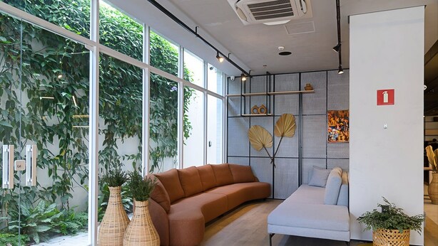 Ein modernes Interieur mit großen Fenstern, einem Sofa, einem Sessel und Wanddekoration.