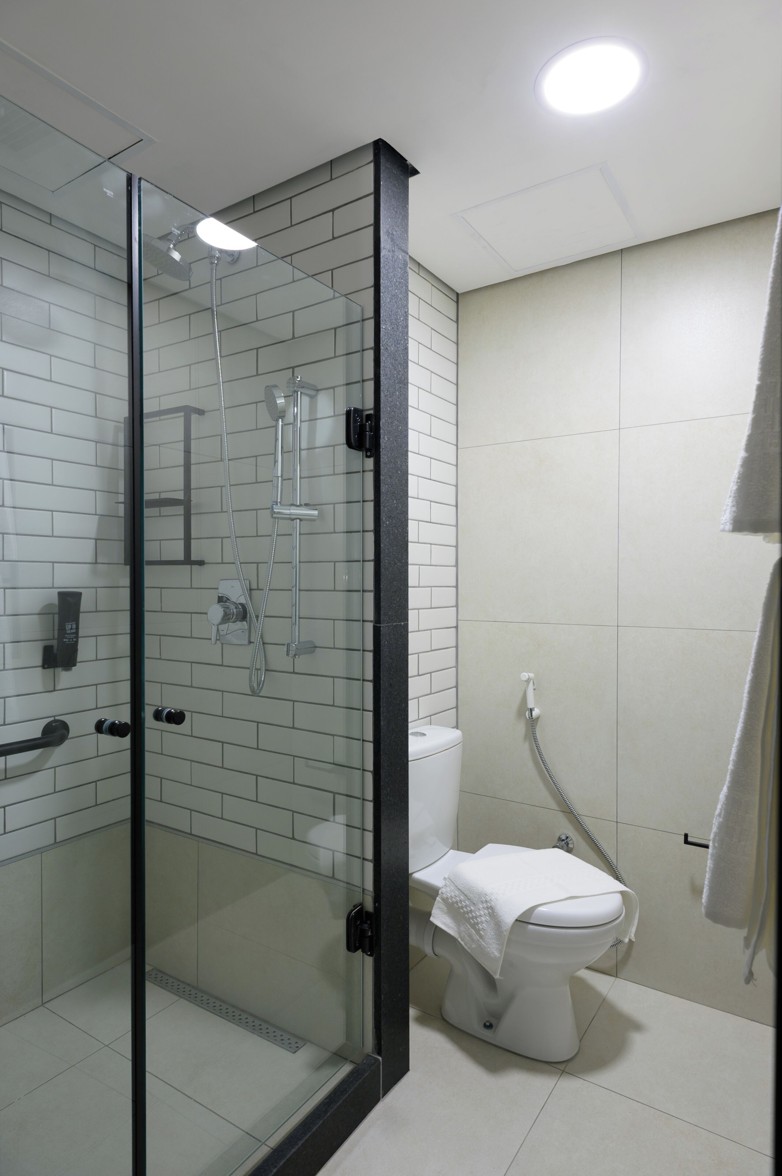 Un baño moderno con cabina de ducha de vidrio, inodoro y toallero.