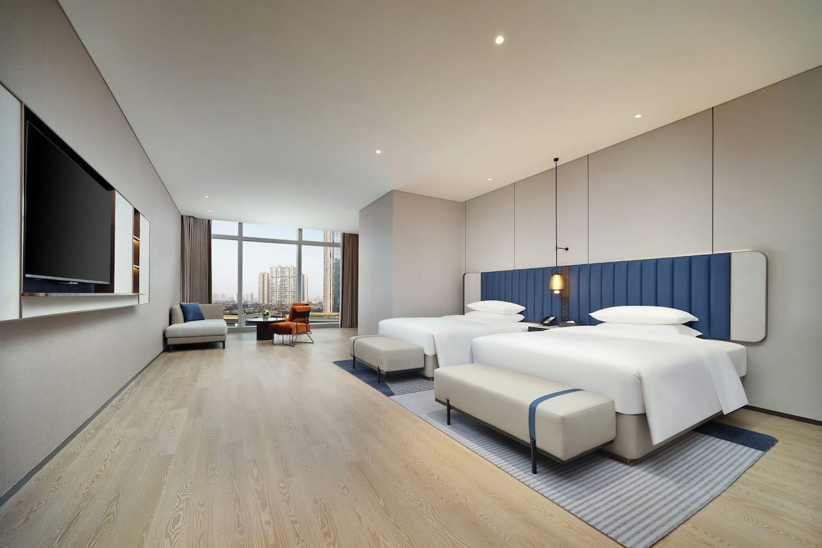 Ein modernes Hotelzimmer mit einem großen Bett, einer Couch, einem Schreibtisch und einem Fernseher.