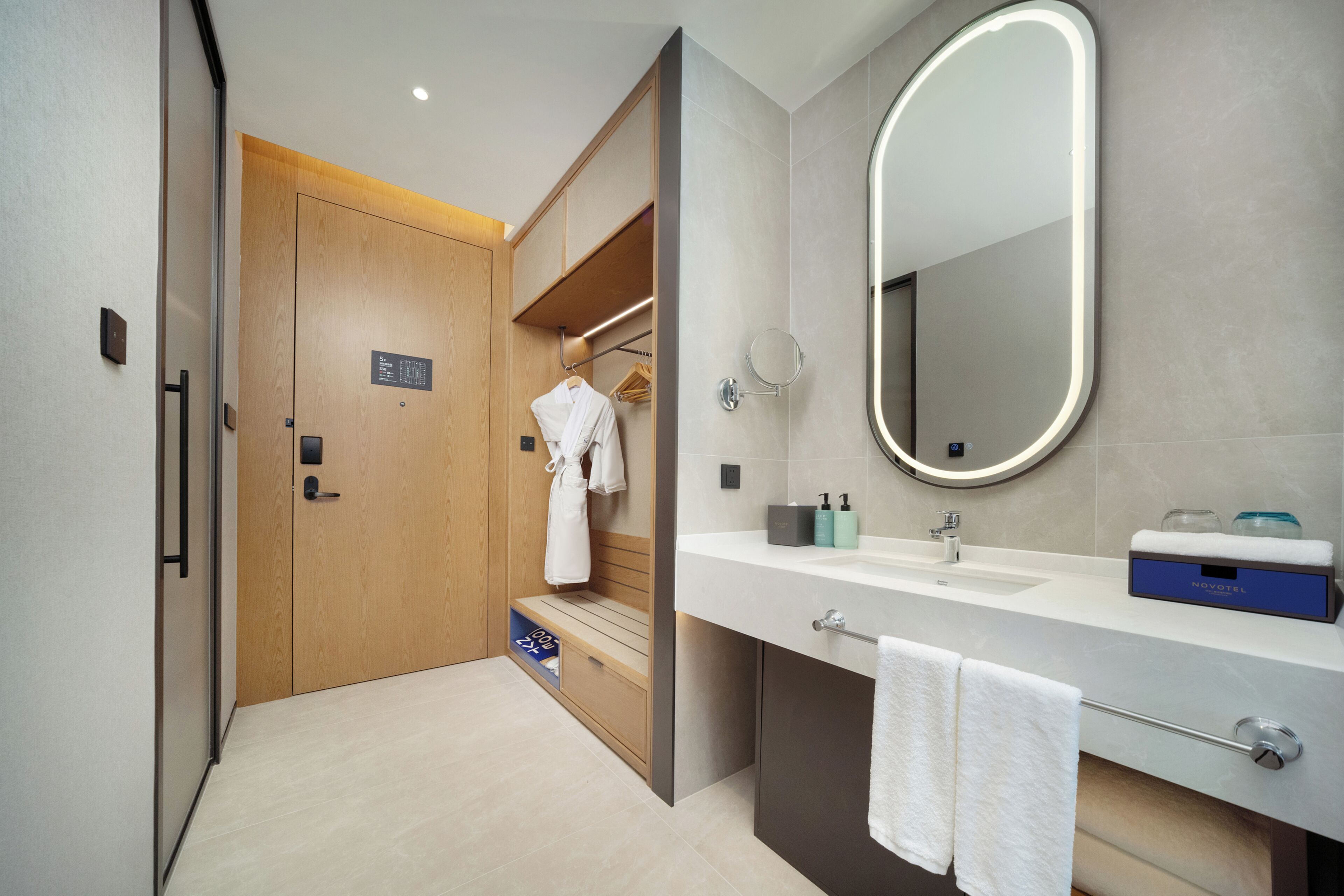Une salle de bain moderne avec une porte en bois, un meuble-lavabo avec un miroir et un banc.