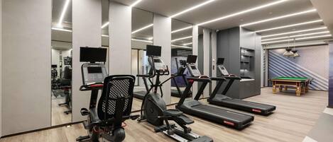 A modern gym with treadmills, elliptical machines, and a pool table.