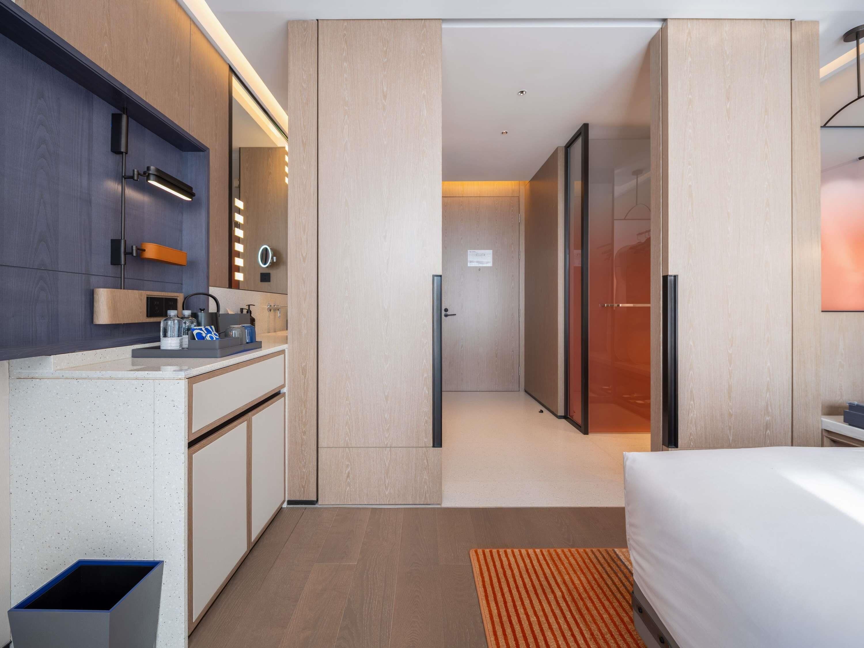 A modern hotel room with a kitchenette, a bed, and a bathroom.