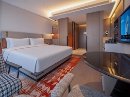 Una habitación de hotel moderna con una cama grande, un escritorio, una silla, un televisor y un baño.