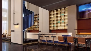 A modern bar area with a curved counter, bar stools, and shelves of bottles. - Novotel Zibo New Hongcheng (Zibo)