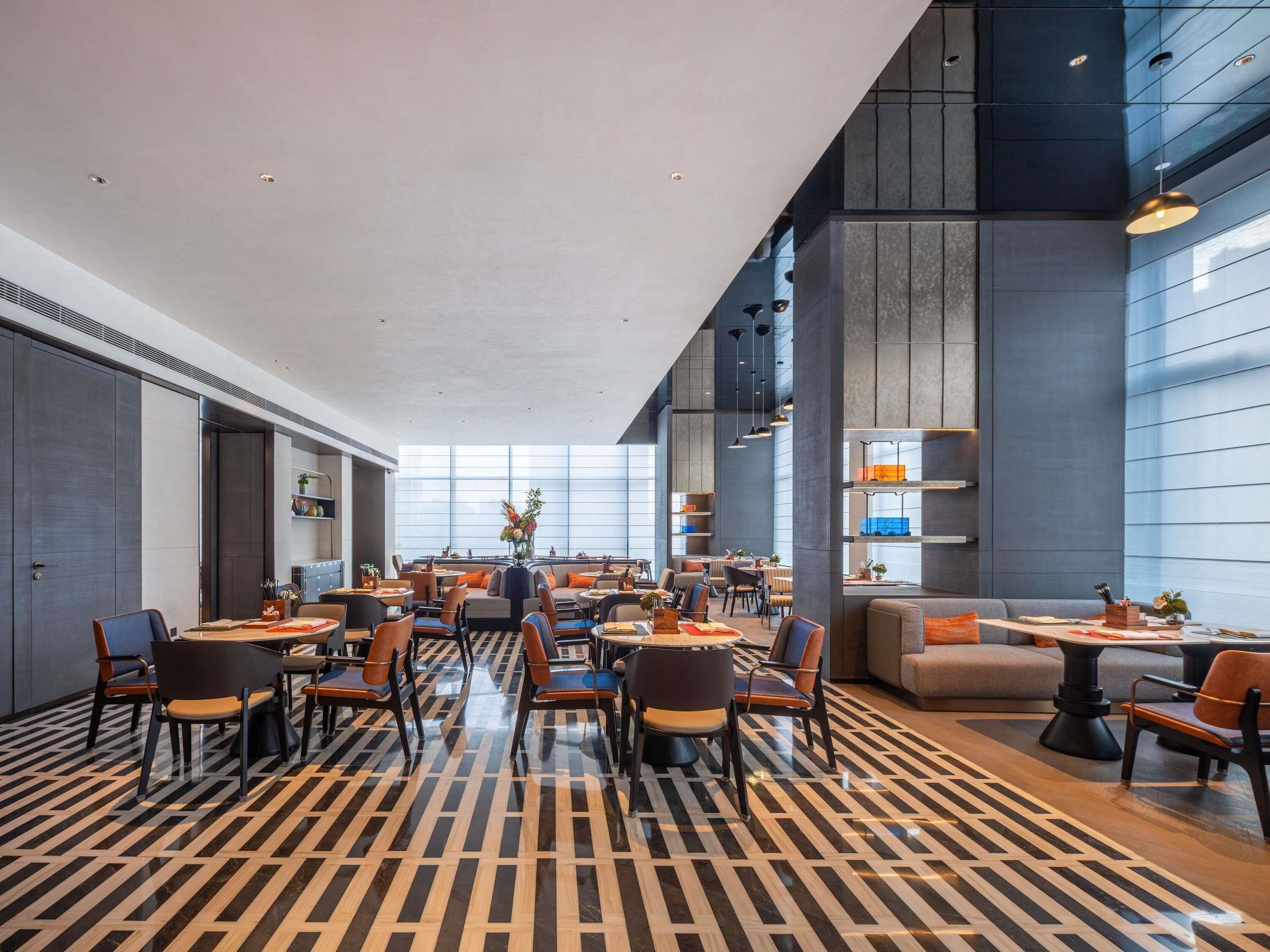 A spacious hotel lobby with high ceilings, modern furniture, and large windows.