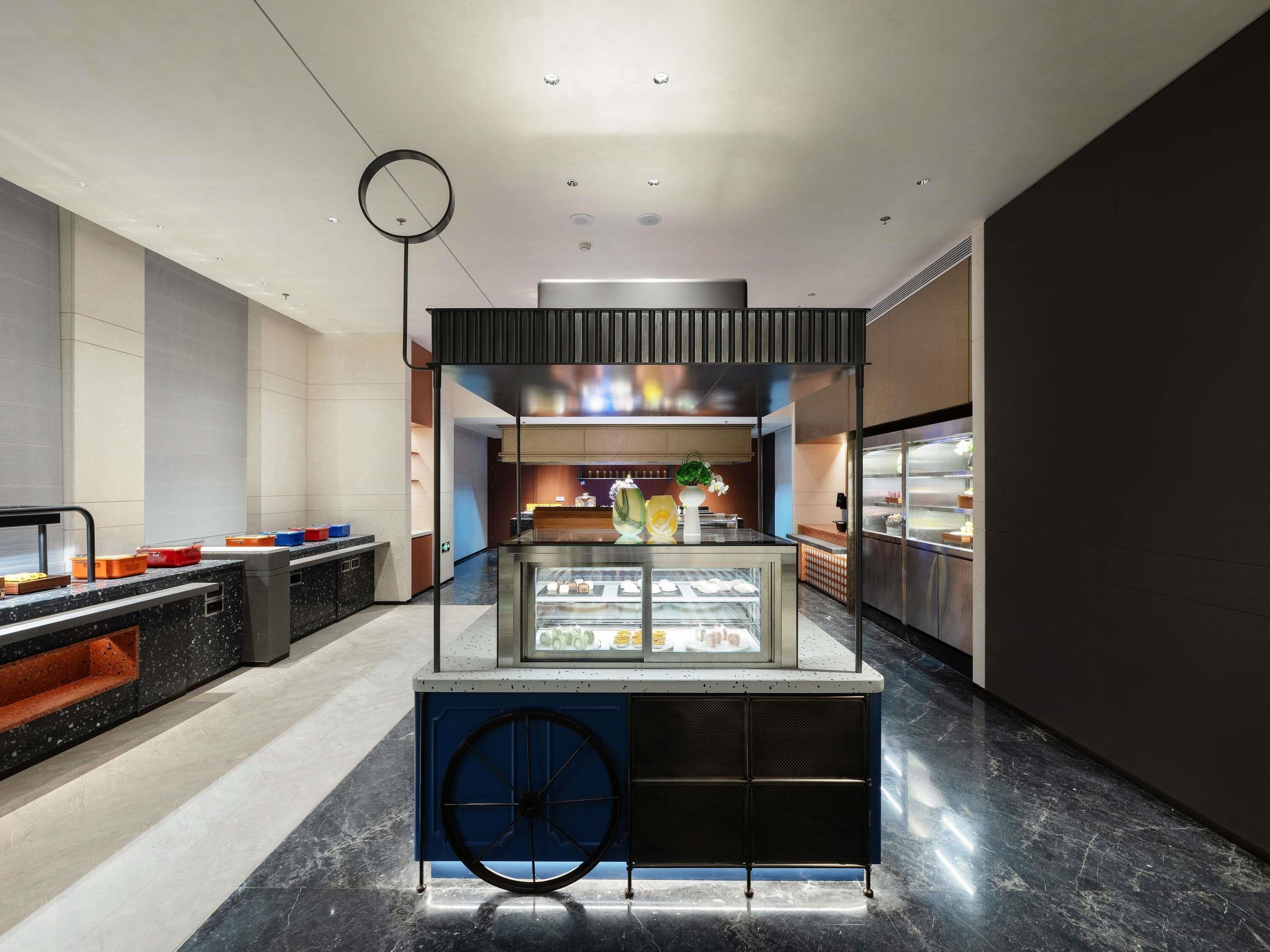 A modern kitchen area with a central display case, a clock, and a counter with food items.