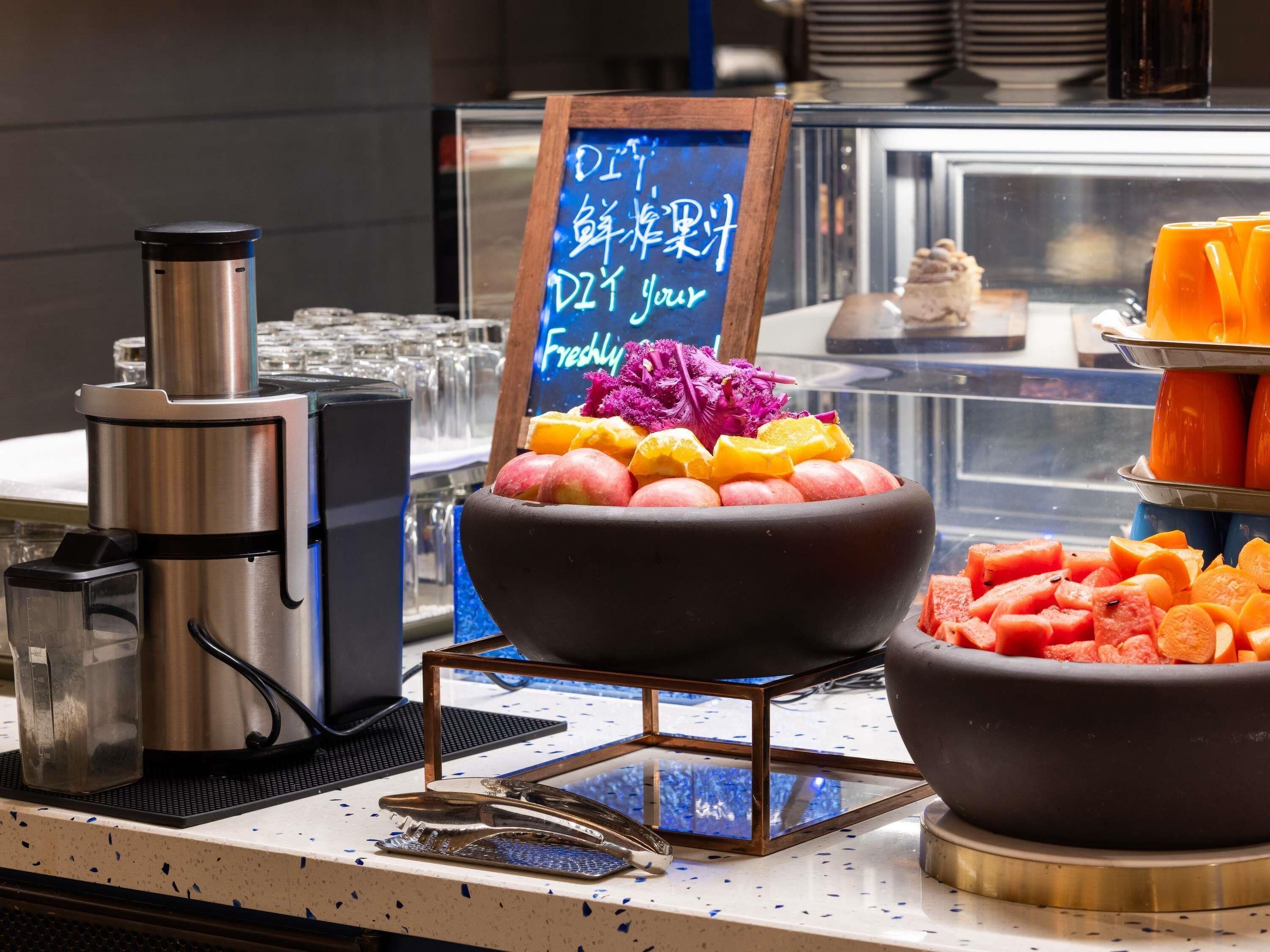 A buffet setup with a coffee machine, a fruit bowl, and a sign with Japanese text.