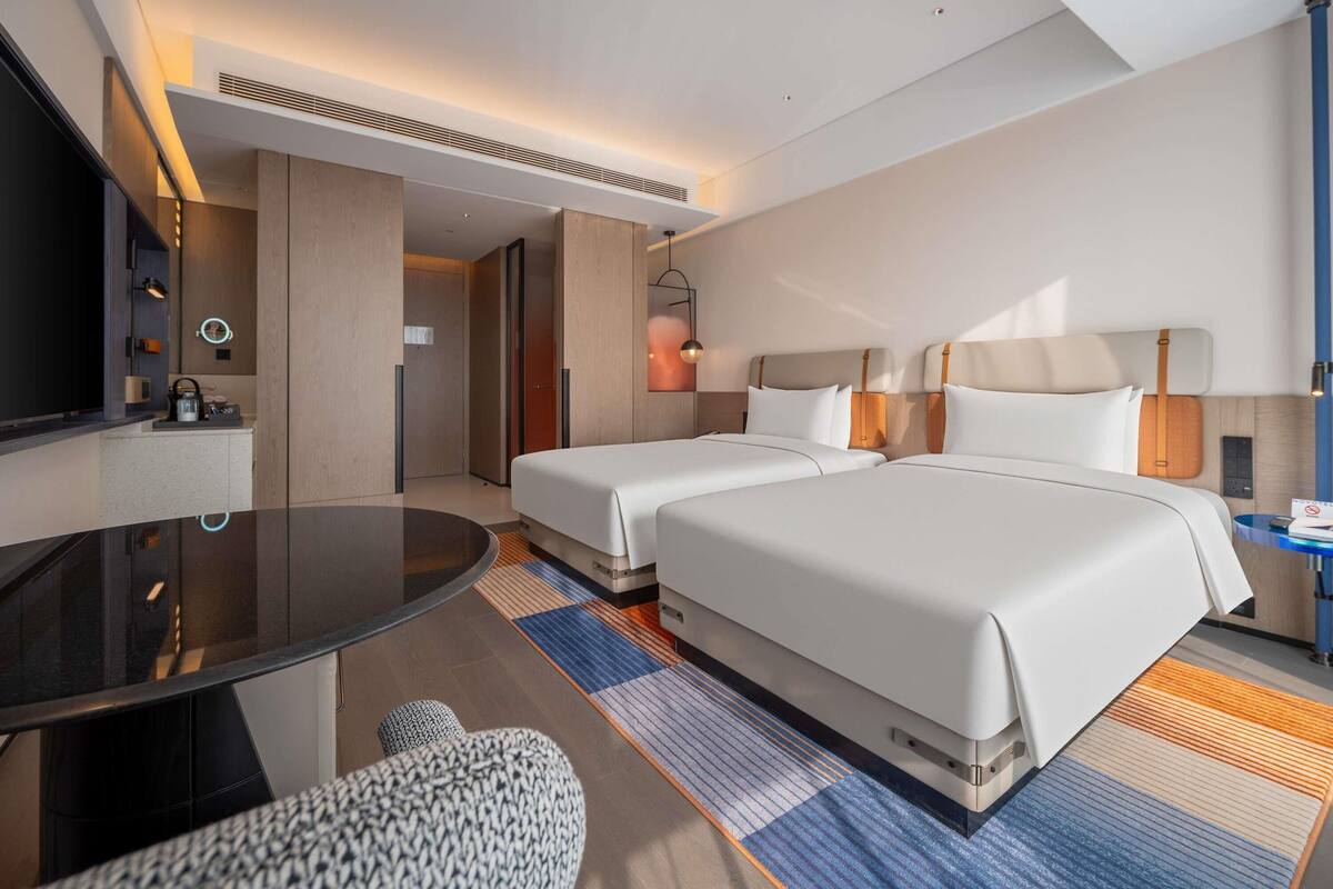 Habitación de hotel con dos camas, televisión, escritorio y baño.