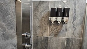 Un espace douche doté d’un mur incurvé, d’un sèche-mains et d’un distributeur de serviettes.