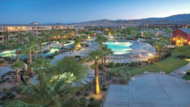 Ein Resort mit mehreren Schwimmbecken, Palmen und einer Bergkulisse.