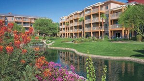 Ein mehrstöckiges Hotel mit Balkonen, einem Innenhof und einem kleinen Teich.
