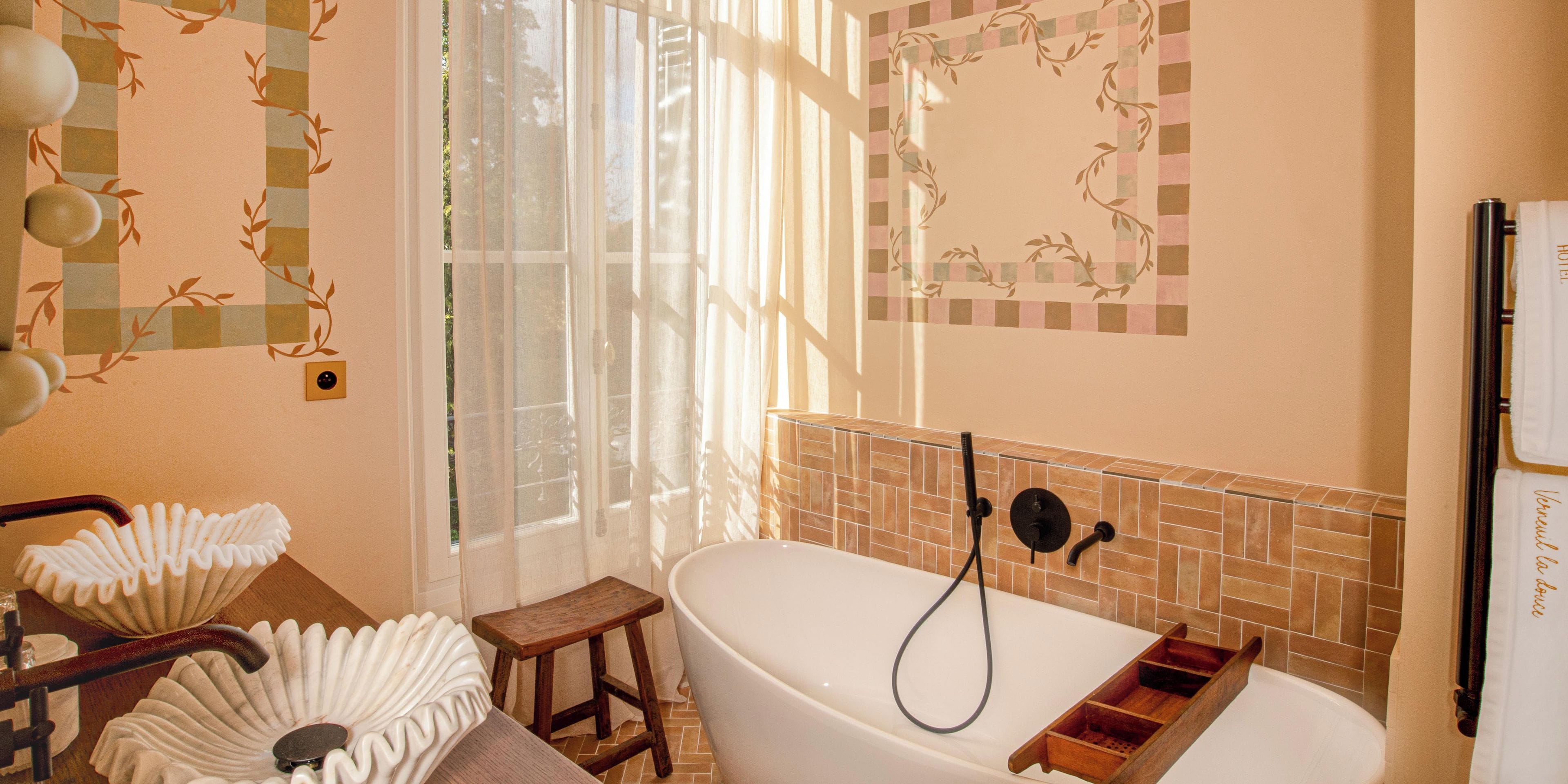 Un bagno con una vasca da bagno, uno sgabello di legno, un portasciugamani e un soffione.
