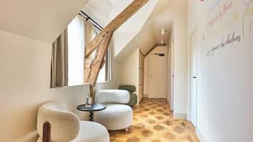 A hallway with a wooden staircase, a white wall with colorful writing, and a patterned floor.