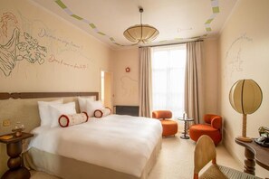 A hotel room with a large bed, a small table, an orange chair, a lamp, and a window with curtains. - Verneuil la douce (Verneuil d'Avre et d'Iton)