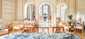 Een luxueuze eetzaal met decoratief meubilair, marmeren vloeren en een grote spiegel.
