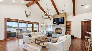A spacious living room with a fireplace, wooden beams, and a large TV.