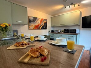 Eine moderne Küche mit Frühstücksbereitstellung, darunter Croissants, Obstteller und Orangensaft.