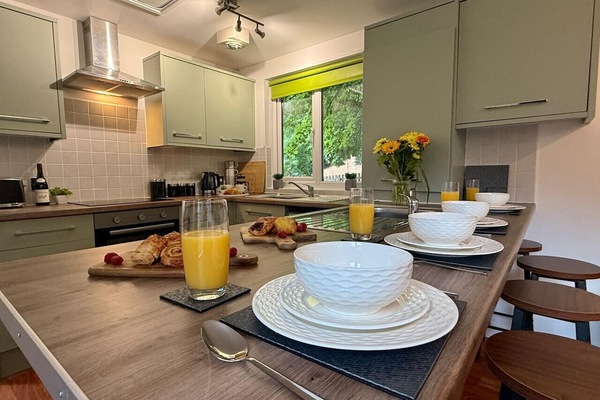 The breakfast bar serves as a place to eat together as a group, here set with white bowls, orange juice, and food on wooden boards.