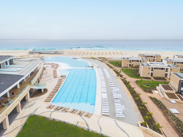 Un resort con piscina, playa y sillas de playa.