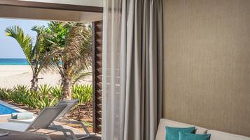 Habitación de hotel con balcón, sofá, cama y vista a la playa.