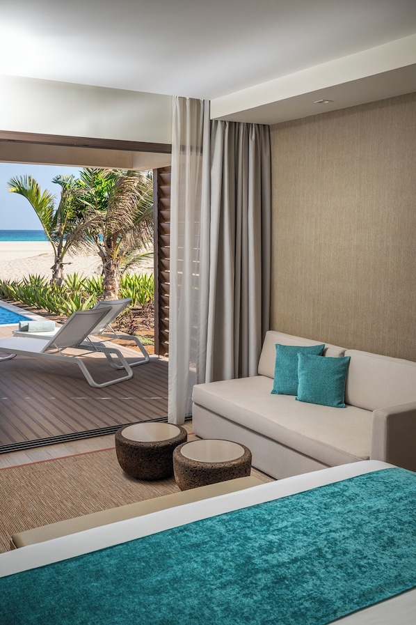 A hotel room with a balcony, a sofa, a bed, and a view of the beach. - Royal Horizon Beijo Mansão - Ponta Sino (Santa Maria)