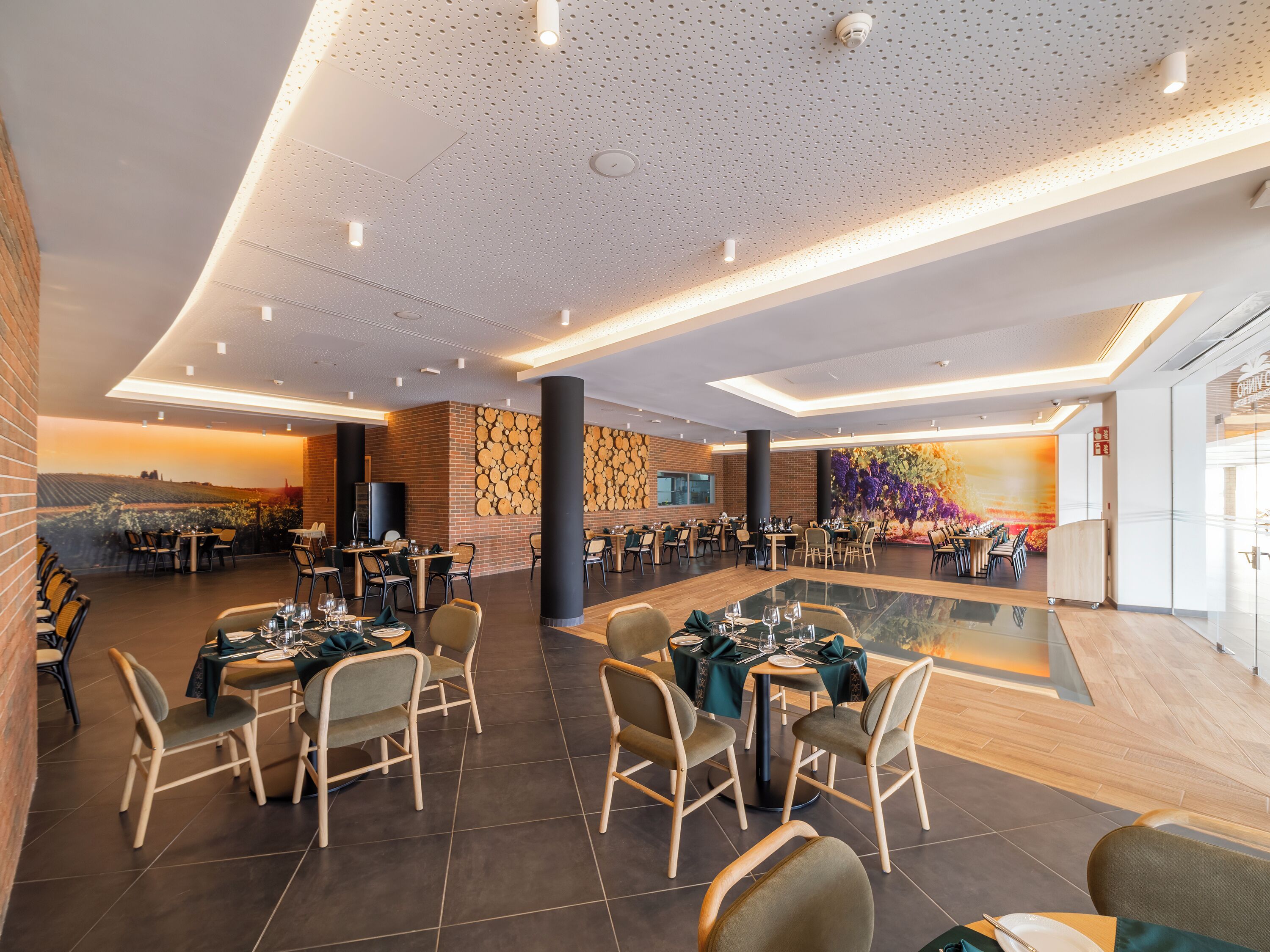 Un restaurant spacieux avec de hauts plafonds, un éclairage moderne et une grande fresque murale.