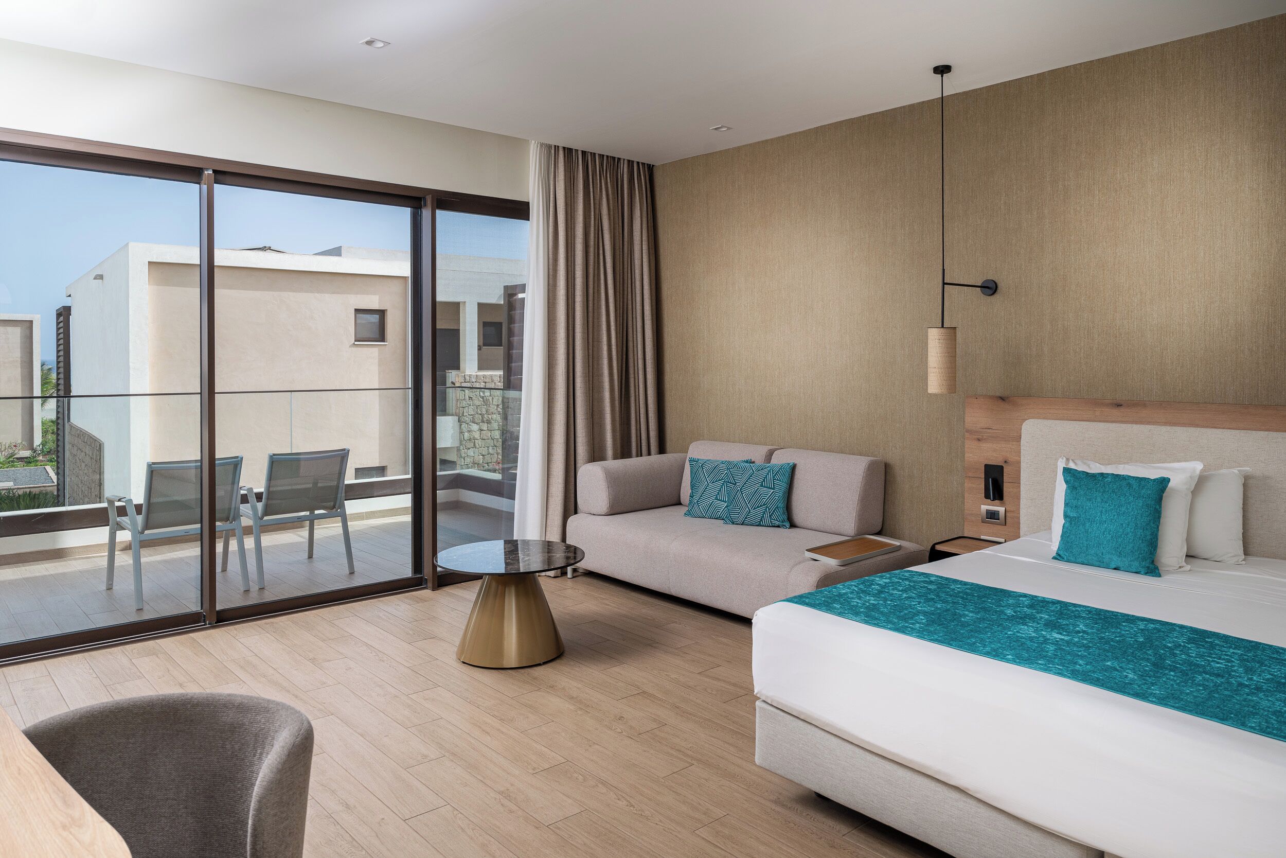 Een moderne hotelkamer met balkon, een bank, een bed en een kleine tafel.
