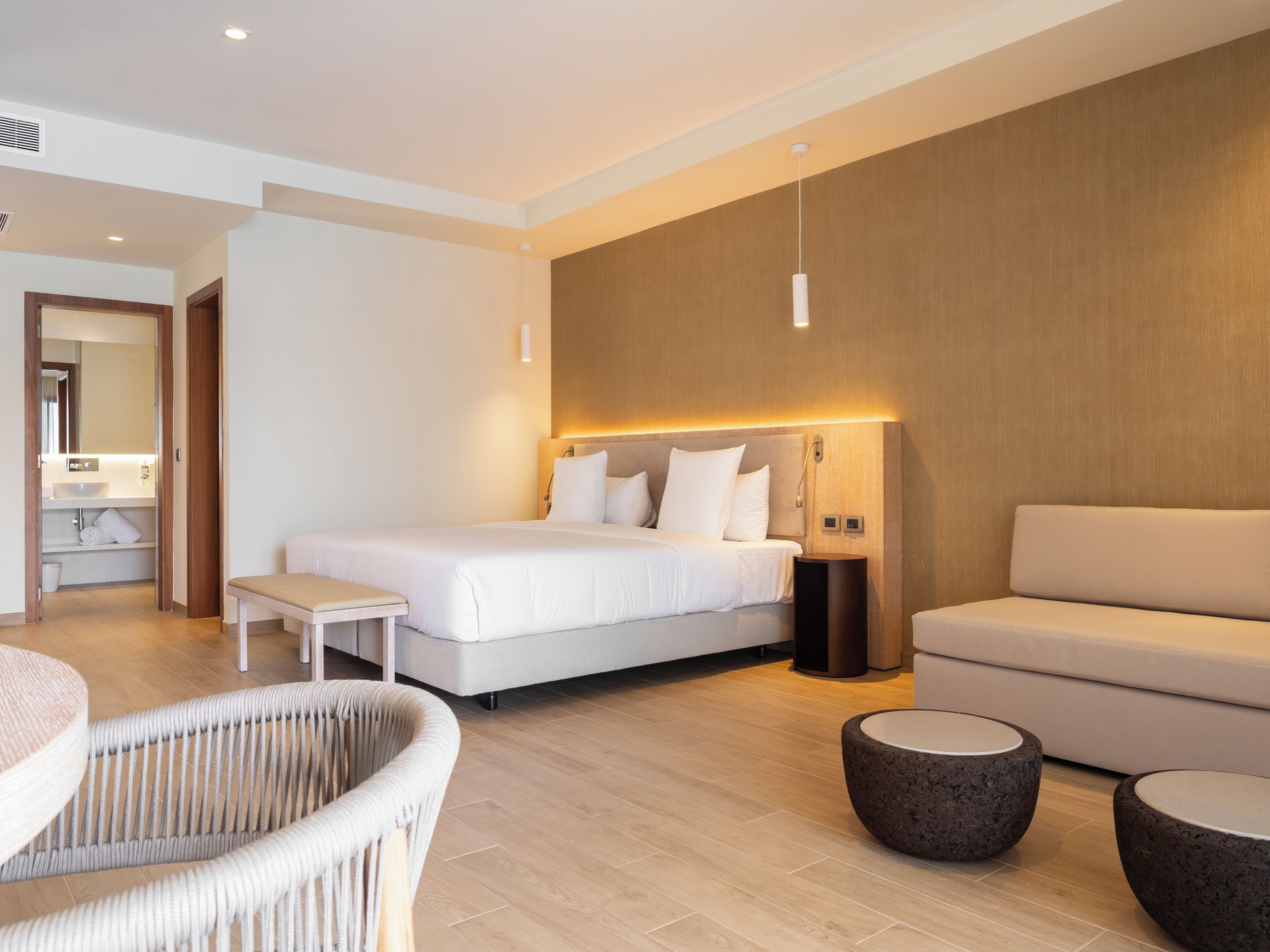 Een moderne hotelkamer met een groot bed, een bank, een klein tafeltje en een stoel.