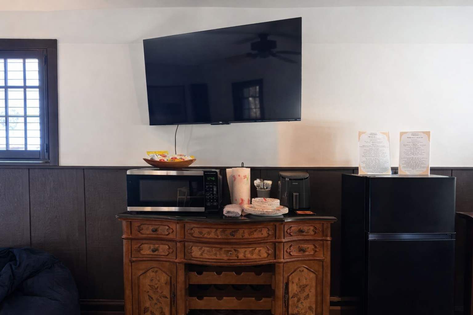 Une cuisine compacte équipée d’un four à micro-ondes, d’une machine à café et d’un réfrigérateur. Un téléviseur est fixé au mur, au-dessus du comptoir.