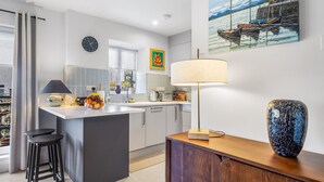Een moderne keuken met een centraal eiland, barstoelen, een eethoek en een groot raam.