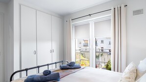 Een slaapkamer met een bed, een witte inbouwkast en een raam met gordijnen.
