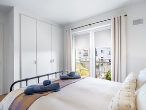 Ein Schlafzimmer mit einem Bett, einem weißen Kleiderschrank und einem Fenster mit Vorhängen.