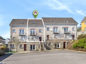 Ein mehrstöckiges Wohngebäude mit Balkonen, einer Stein-Fassade und blauem Himmel.