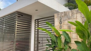 A modern building facade with a metal gate and a stone wall with the number 208. - Beautiful comfortable home with swimming pool (Mérida)